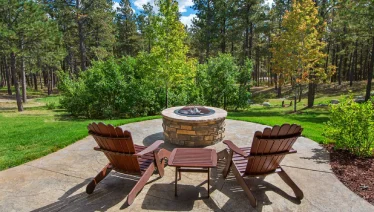 Stone firepit with Adirondack chairs, built by The Grounds Guys service professional