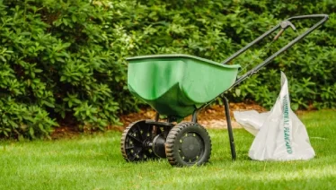 Fertilizer spreader and bag on the lawn, ready for use by The Grounds Guys service professional